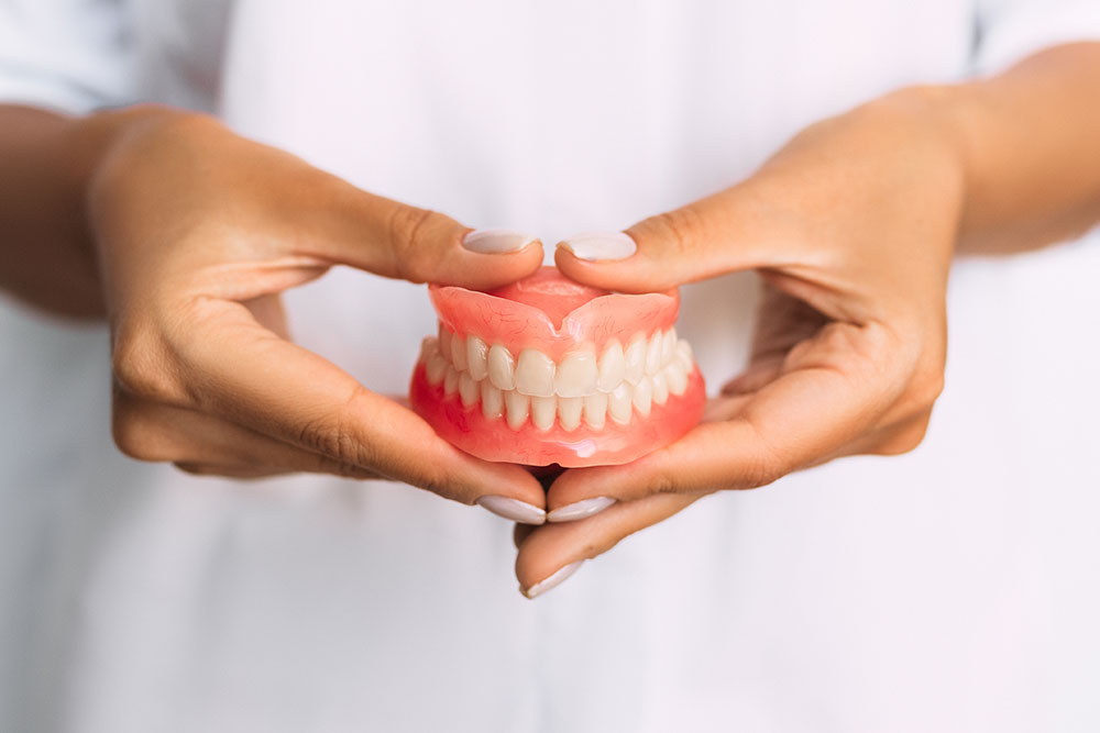 dentist holding dentures in her hands