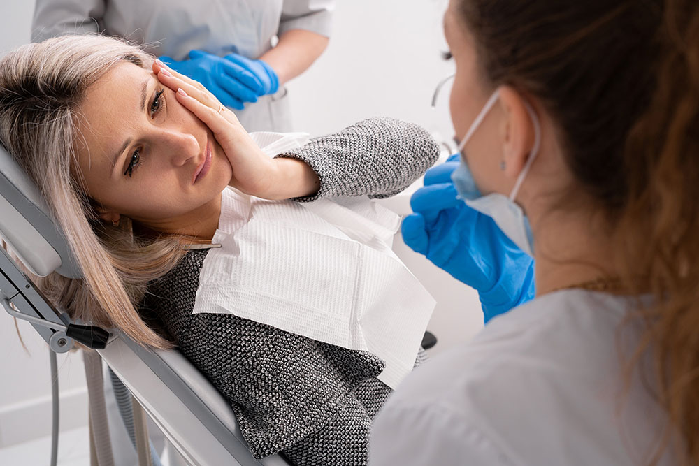 beautiful caucasian girl with toothache sits in a dental chair. Professional dentist helps his female patient in pain.
