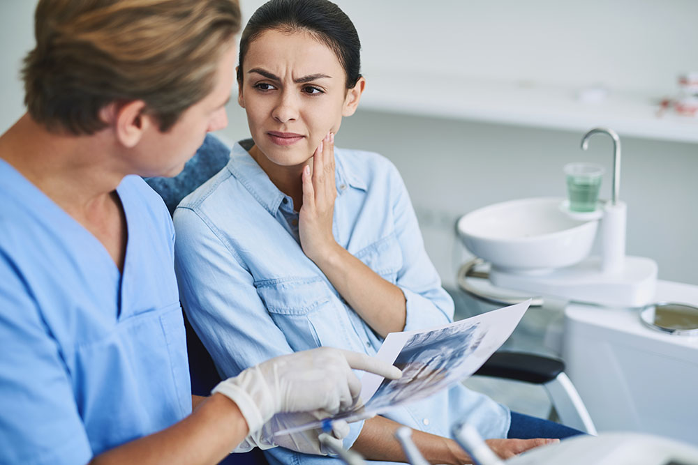 woman touching her cheeck from jaw paint at dentist office