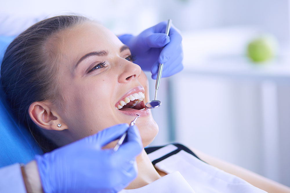 Young Female patient with open mouth examining dental inspection at dentist office