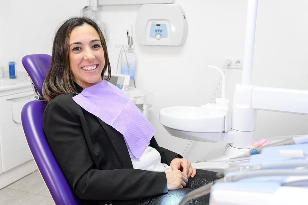 Portrait of smiling young woman lying in dental chair and looking at camera, copy space.